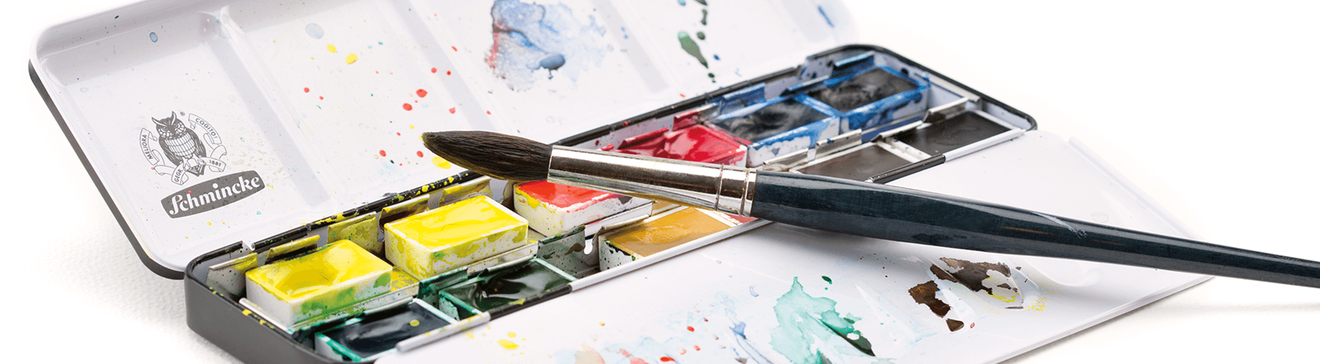 Artist-grade Schmincke watercolour paint palette with a brush, showcasing vibrant colors and smooth application.