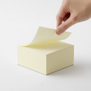 Hand pulling a sheet from MD Block memo pad, showcasing its grid design and quality paper.