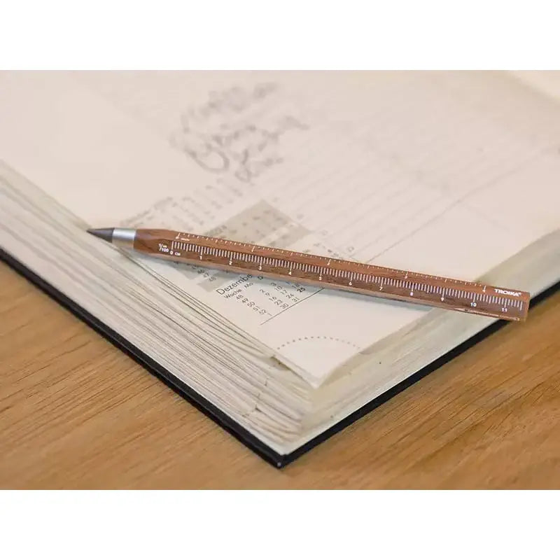 Construction Endless Walnut Pencil resting on an open planner, showcasing its multitasking design and ruler feature.
