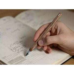 Person using a Construction Endless Walnut Pencil on an open planner, showcasing elegant design and functionality.