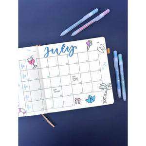 July planner with beach-themed doodles, featuring Gelly Roll Stardust glitter gel pens in various colors on a navy background.