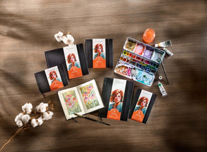 Hahnemühle Watercolour Books on a table with watercolor palette, showcasing traditional deckle edge design and artistic materials.