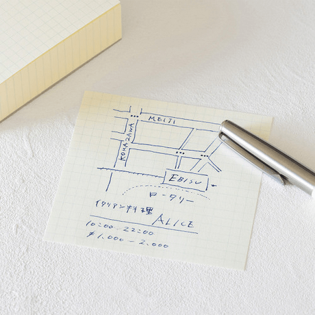 MD Block memo pad with handwritten map and notes on grid paper beside a silver pen.