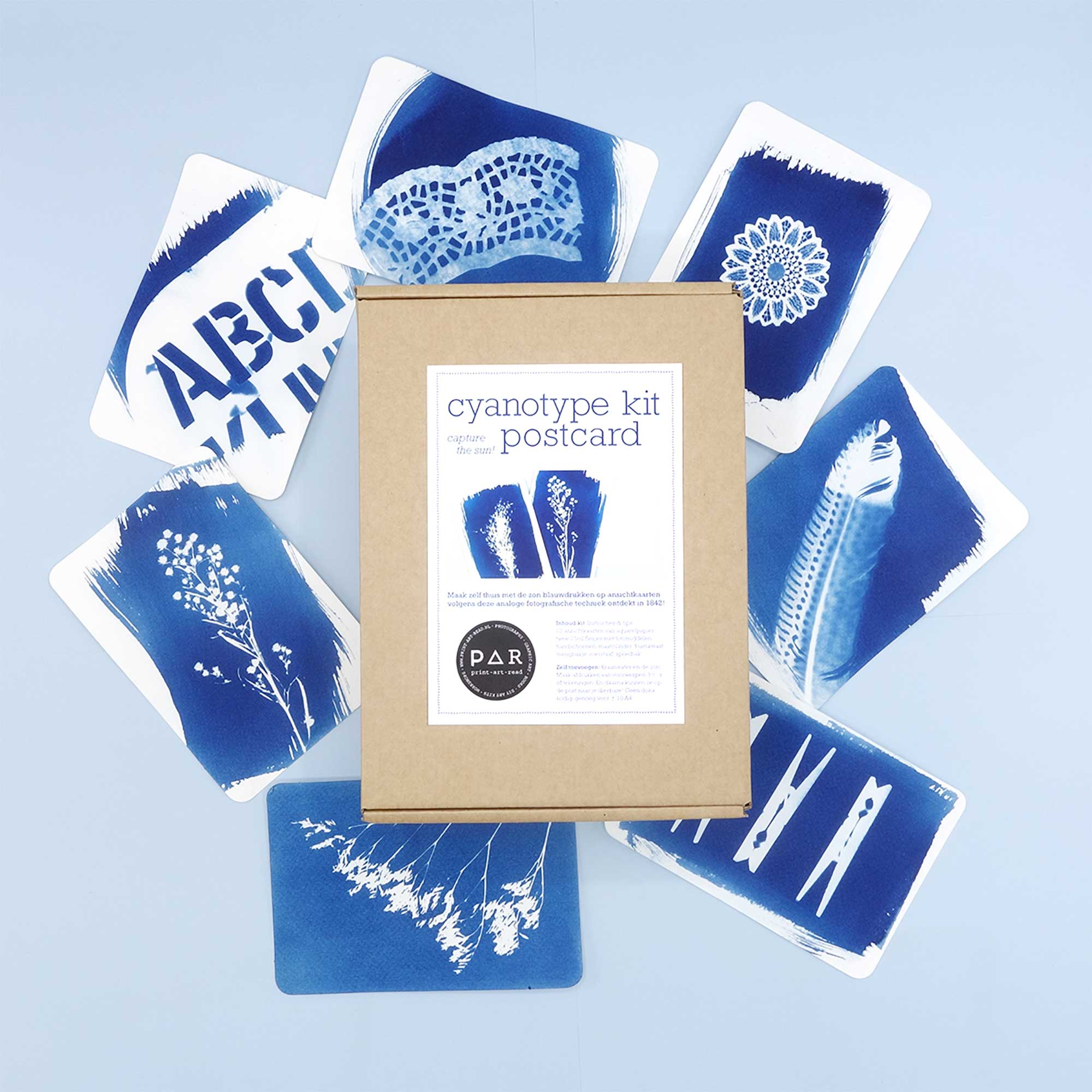 PAR Cyanotype Postcard Kit box surrounded by Prussian blue sun print postcards