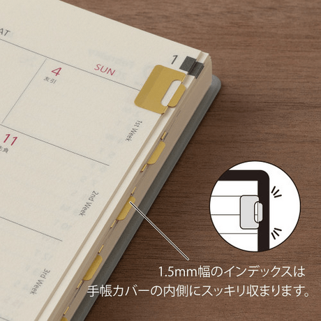 Midori Index Clip<S> Chiratto Brass attached to a planner page, showcasing its slim design and functionality.