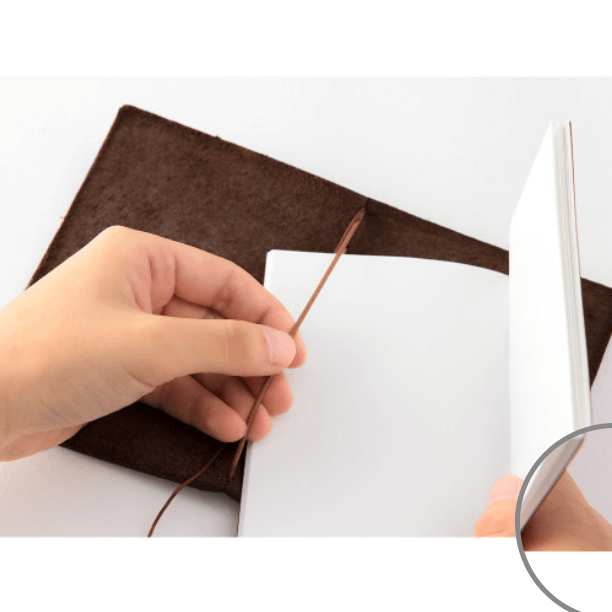 Hands holding TRAVELER’S notebook – Passport Size Brown with leather cover and MD Paper notebook, ideal for travel and daily use.