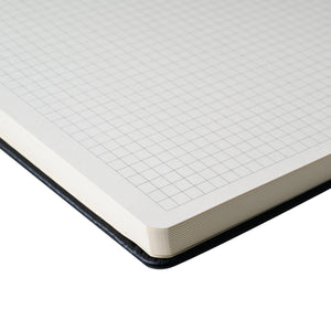 Close-up of squared cream white paper in the Sakura A4 hard cover notebook, featuring rounded corners and durable design.