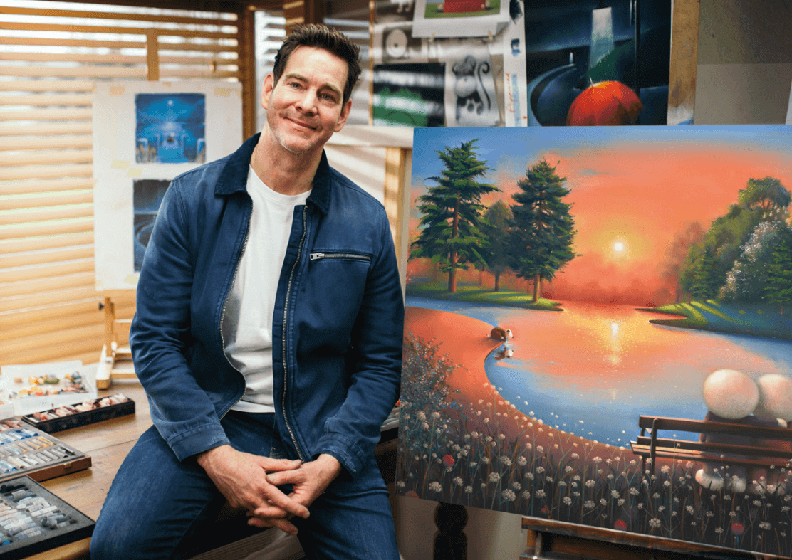 Artist with vibrant landscape painting in studio setting