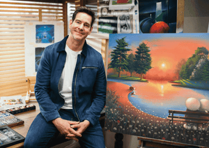 Artist with vibrant landscape painting in studio setting