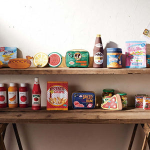 Variety of fun and colorful novelty pouches shaped like food items displayed on wooden shelves.