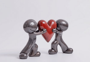 Heart to Heart Bronze Sculpture by Doug Hyde featuring two figures holding a red heart, symbolizing trust and emotional closeness.