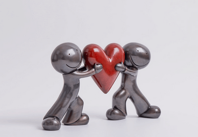 Heart to Heart Bronze Sculpture by Doug Hyde featuring two figures holding a red heart, symbolizing trust and emotional closeness.
