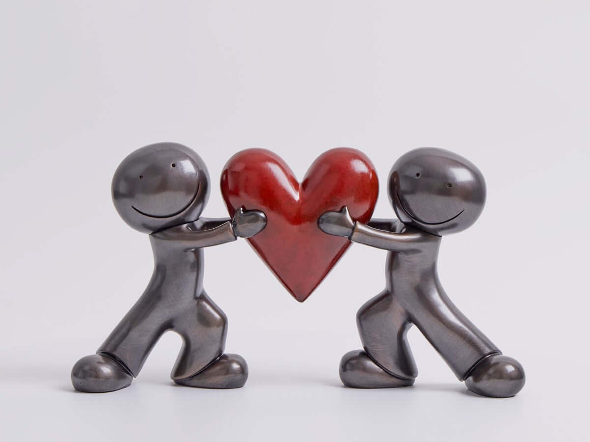 Heart to Heart Bronze Sculpture by Doug Hyde featuring two figures with a red heart, symbolizing trust and emotional closeness.