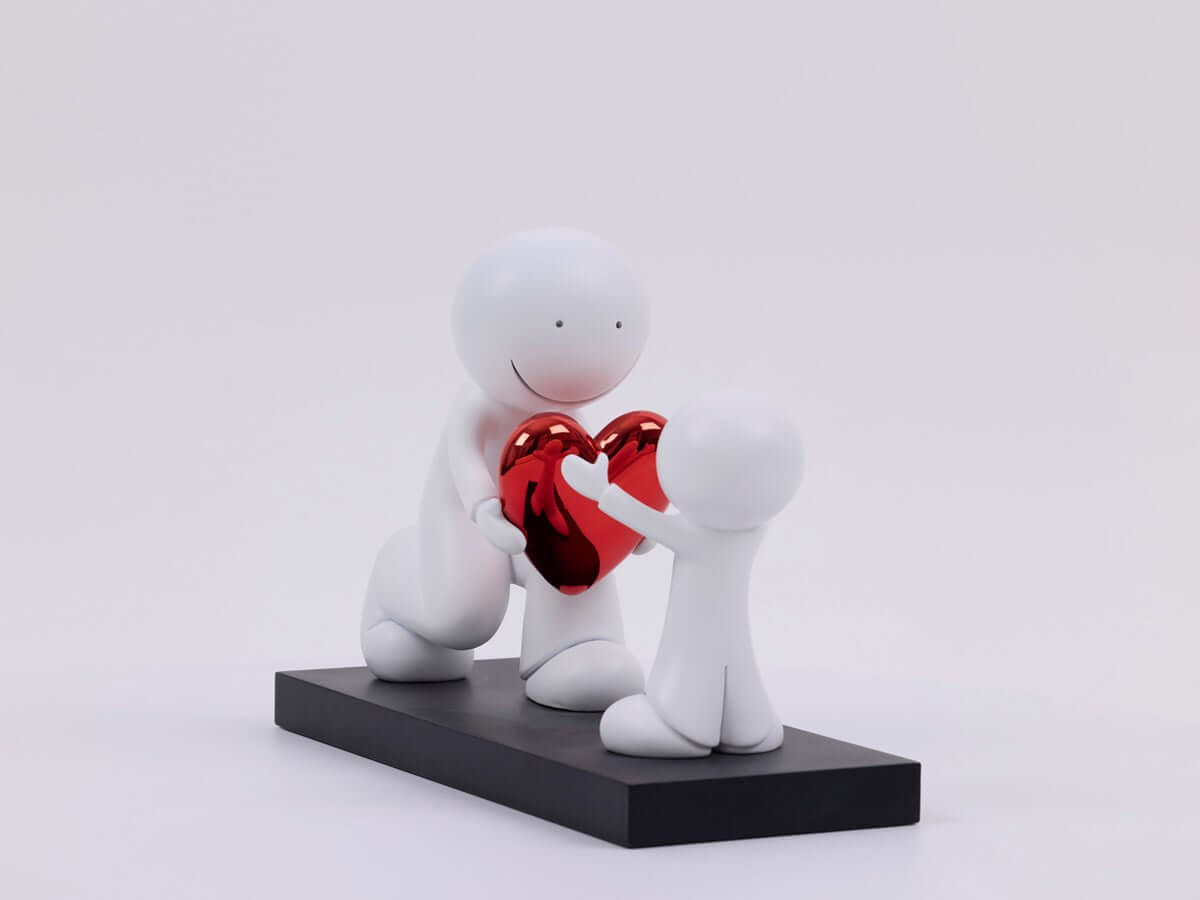The Greatest Gift Sculpture by Doug Hyde featuring figures sharing a red heart, symbolizing generosity and affection.