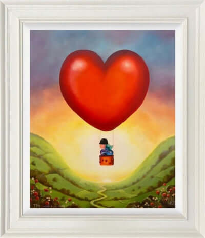 Framed artwork 'The World is Ours by Michael Abrams' featuring a heart-shaped hot air balloon over a scenic landscape.